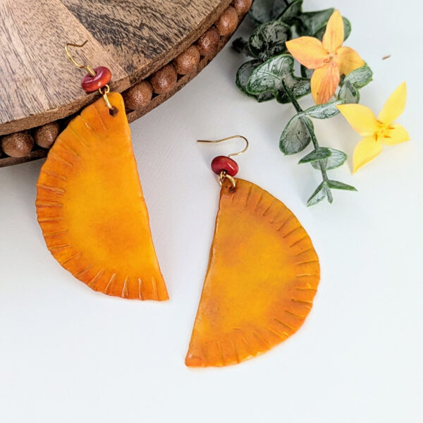 big empanada food earrings on round wood display