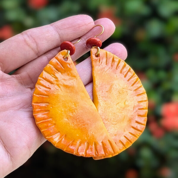 long empanada earrings in front of puerto rico flowers