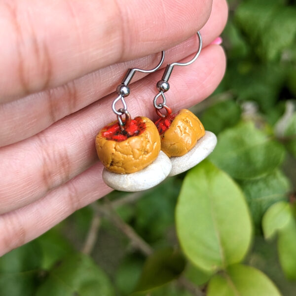 mini mofongo earrings hanging from hand