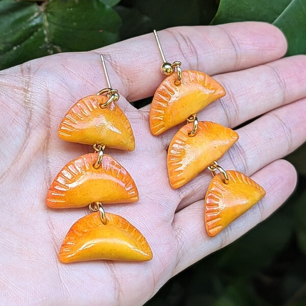 handmade empanada earrings shown on hand