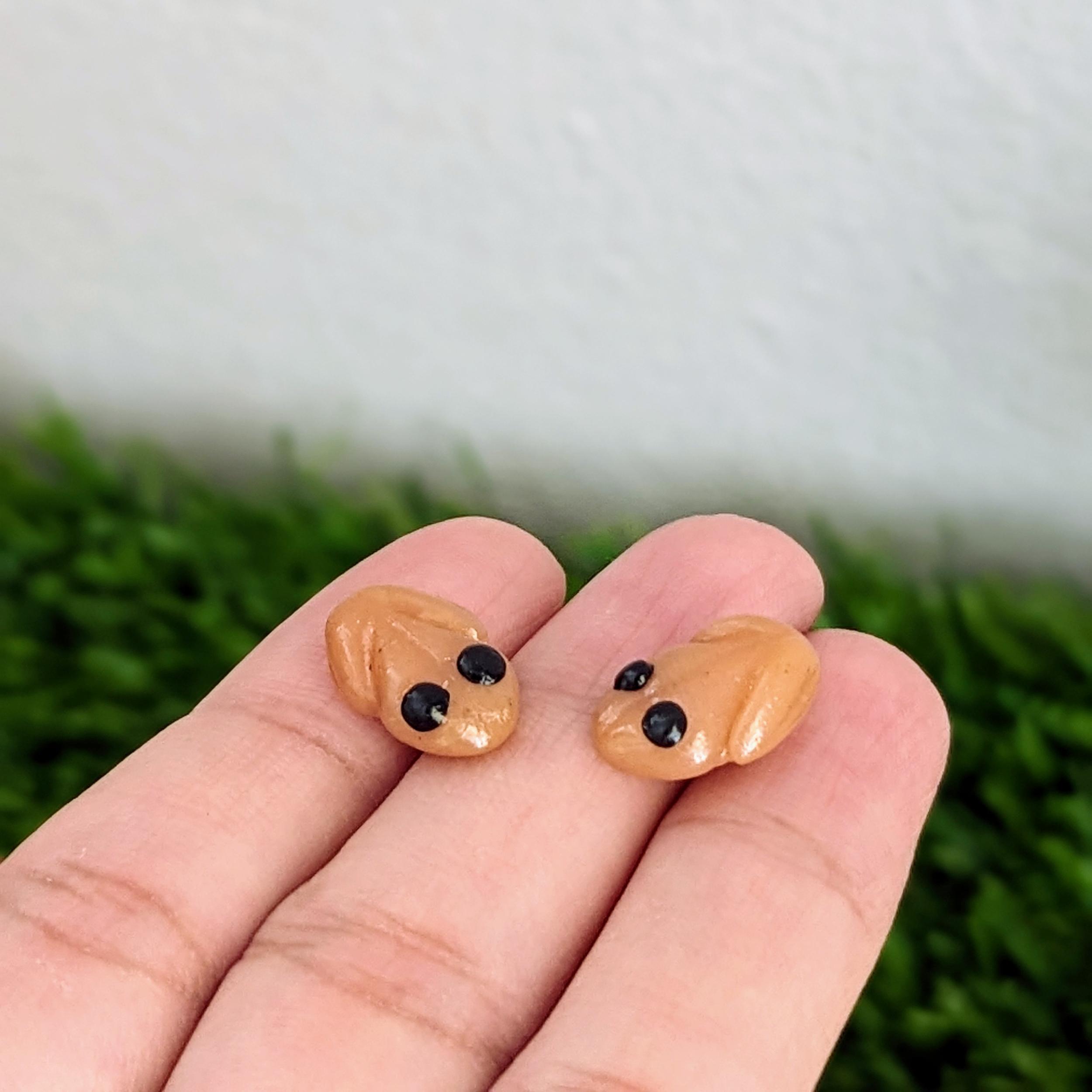 handmade coqui earrings on fingers with grass