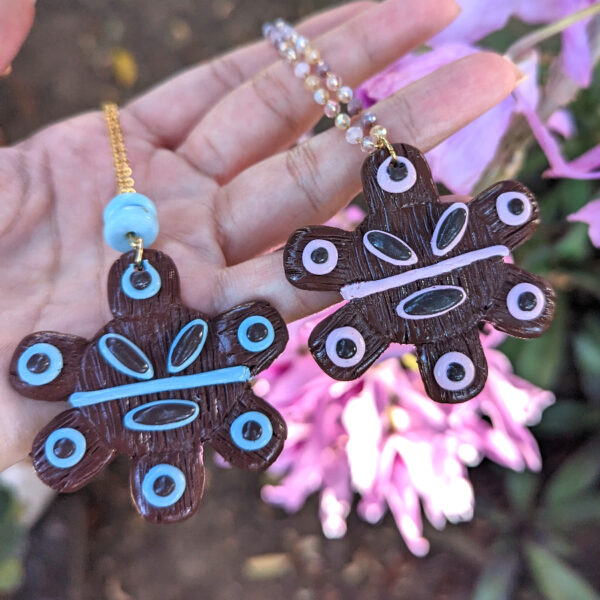 taino necklaces in front of pink flower