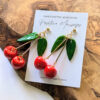 gold cherry earrings on brown log