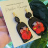 coqui earrings in front of hibiscus leaves