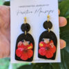 coqui earrings in front of hibiscus plant