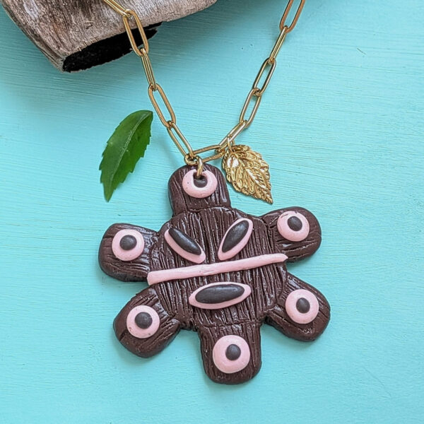 sol taino necklace next to small leaf