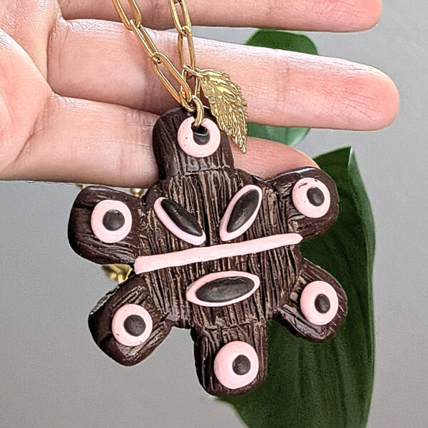 taino sun necklace shown on artisans hand